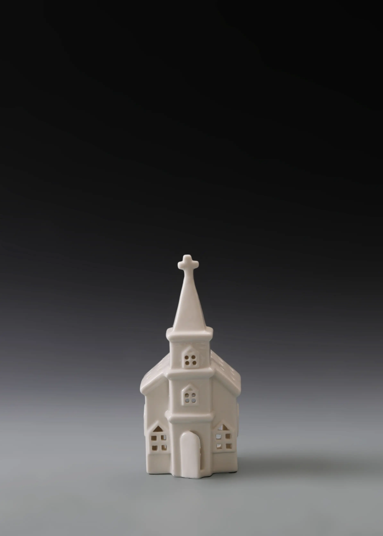 221A tall steeple house in matte white ceramic with a pointed steeple and illuminated arched windows.