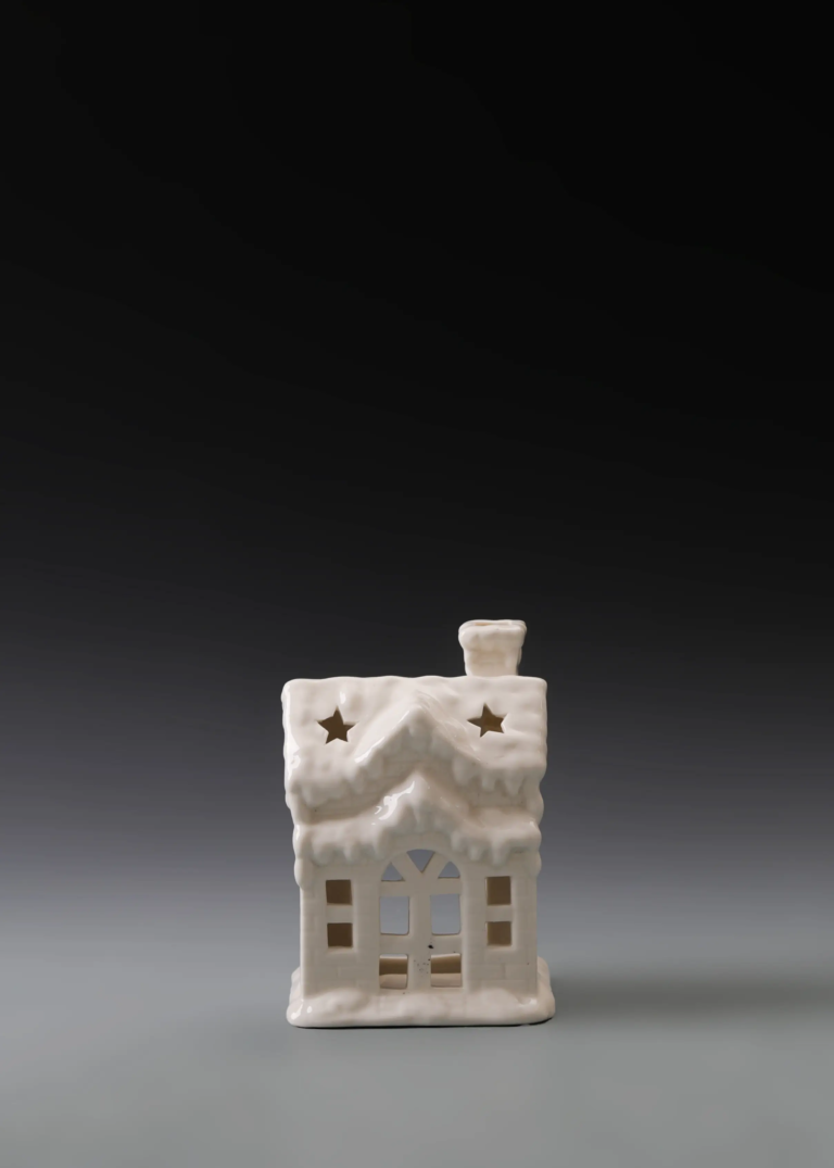 223A snow roof house in matte white ceramic with a pronounced snowy roof design and illuminated windows.