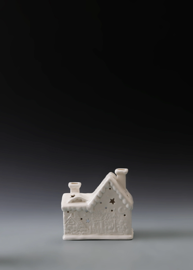 230A low snow cottage in matte white ceramic with a wide profile, snowy roof details and illuminated openings.
