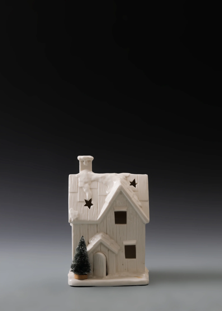 231A snowy star house in matte white ceramic with snowy roof details, star accents and illuminated windows.