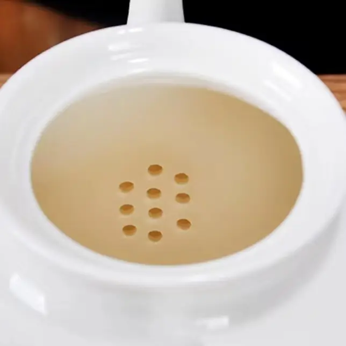 Close-up of the built-in filter holes inside a porcelain teapot, showing the tea straining design.