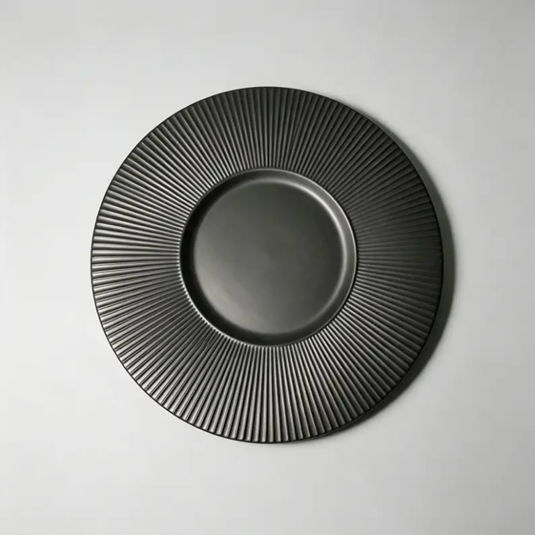 Black fluted ceramic plate with dense radial texture and matte surface finish