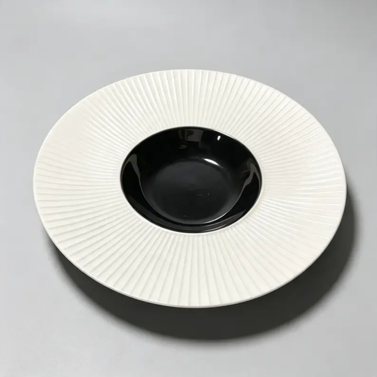 Black and white fluted hat rim ceramic plate with contrasting colors and radial texture