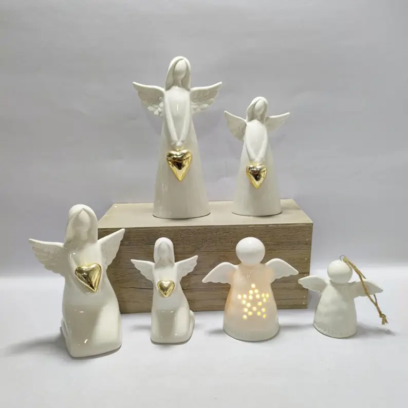Ceramic angel figurines in glossy white finishes with gold heart details and varied sculptural forms.