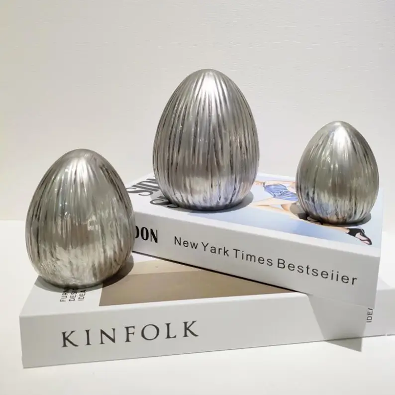Easter ceramic display featuring a silver ribbed egg ornament with raised vertical texture alongside complementary seasonal decor.
