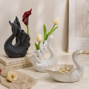 Swan ceramic pieces used as floral holders and jewelry storage containers, combining decorative display with practical functions.