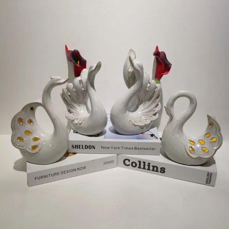 Group of reactive glaze white swan ceramic pieces with elegant curved designs and glossy surface details for romantic seasonal displays.