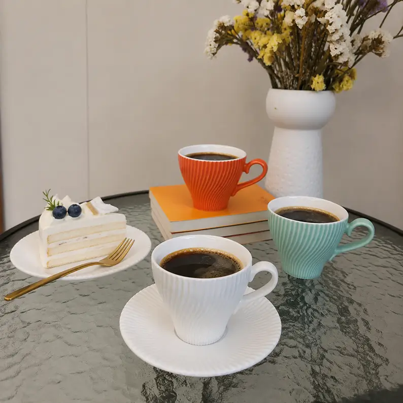 Spiral-textured ceramic coffee cups and saucers served with coffee and dessert in an afternoon tea setting.