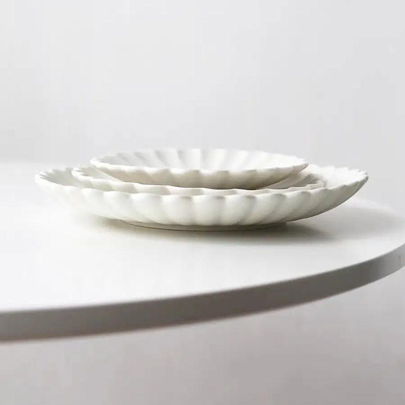 Close-up of ivory white chrysanthemum ceramic plate, showing petal edge texture and matte glaze finish