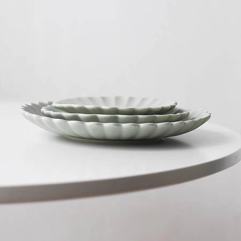 Close-up of light celadon chrysanthemum ceramic plate, showing delicate petal texture and subtle glaze tone