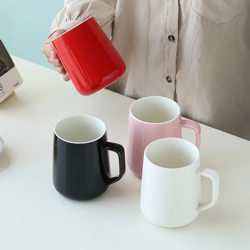 Ceramic mugs in different colors arranged with matching spoons for a contemporary kitchen and dining scene.