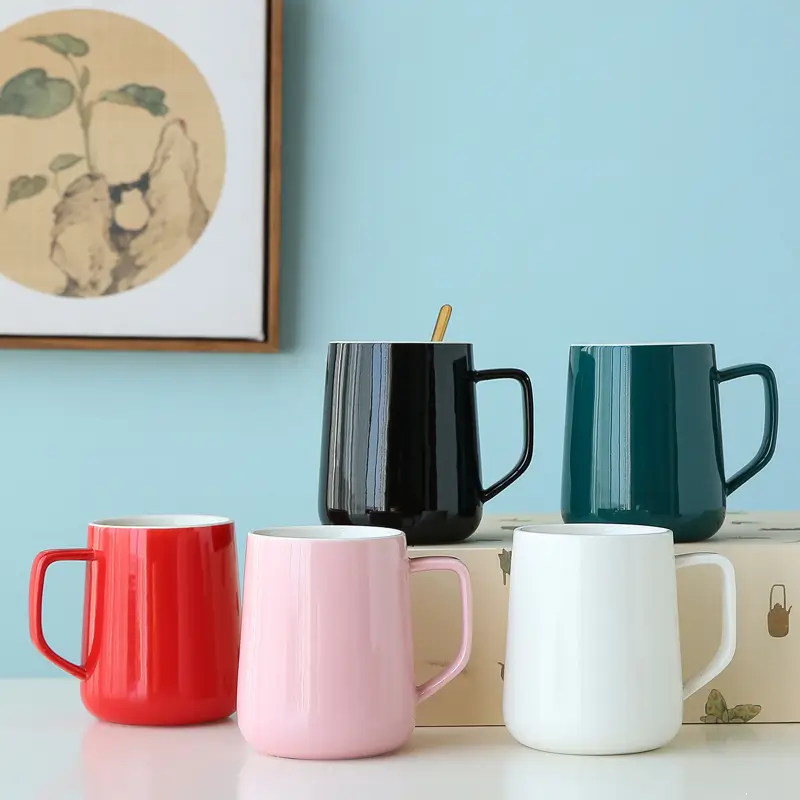 Five ceramic mugs with matching spoons displayed together showing multiple color options for modern drinkware collection.